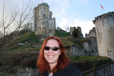 Red headed women standing n front of an ancient castle in France.