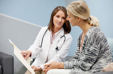 physician assistant showing medical chart to women patient